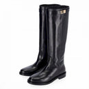 Stivale in pelle nera stile cavallerizzo tubolare con cinturino giro polpaccio chiuso da fibbia metallica color oro.