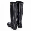 Stivale in pelle nera stile cavallerizzo tubolare con cinturino giro polpaccio chiuso da fibbia metallica color oro.